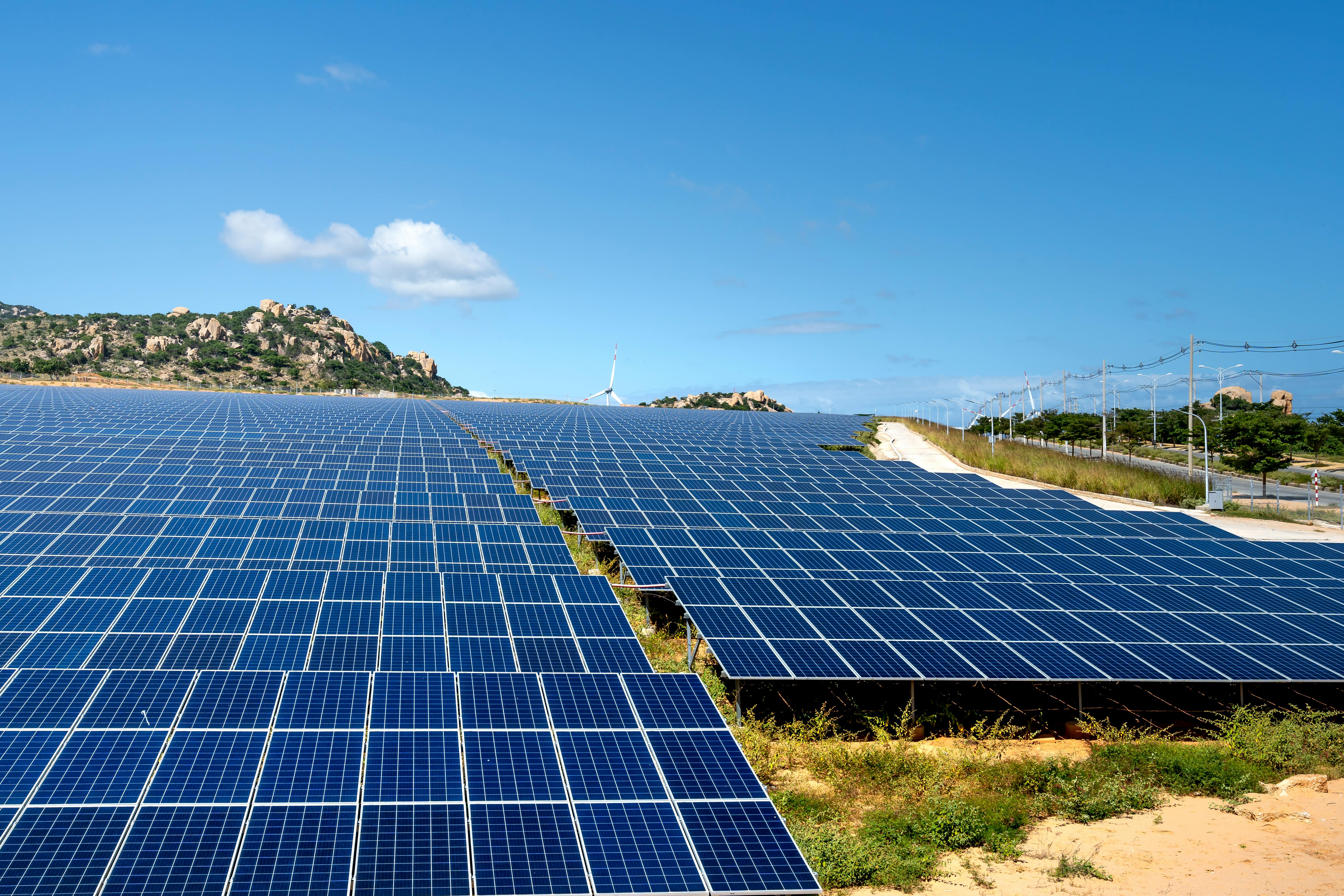 Solar farm with wind turbine, Ninh Thuận Province, Vietnam — clean energy infrastructure driving purposeful economic development