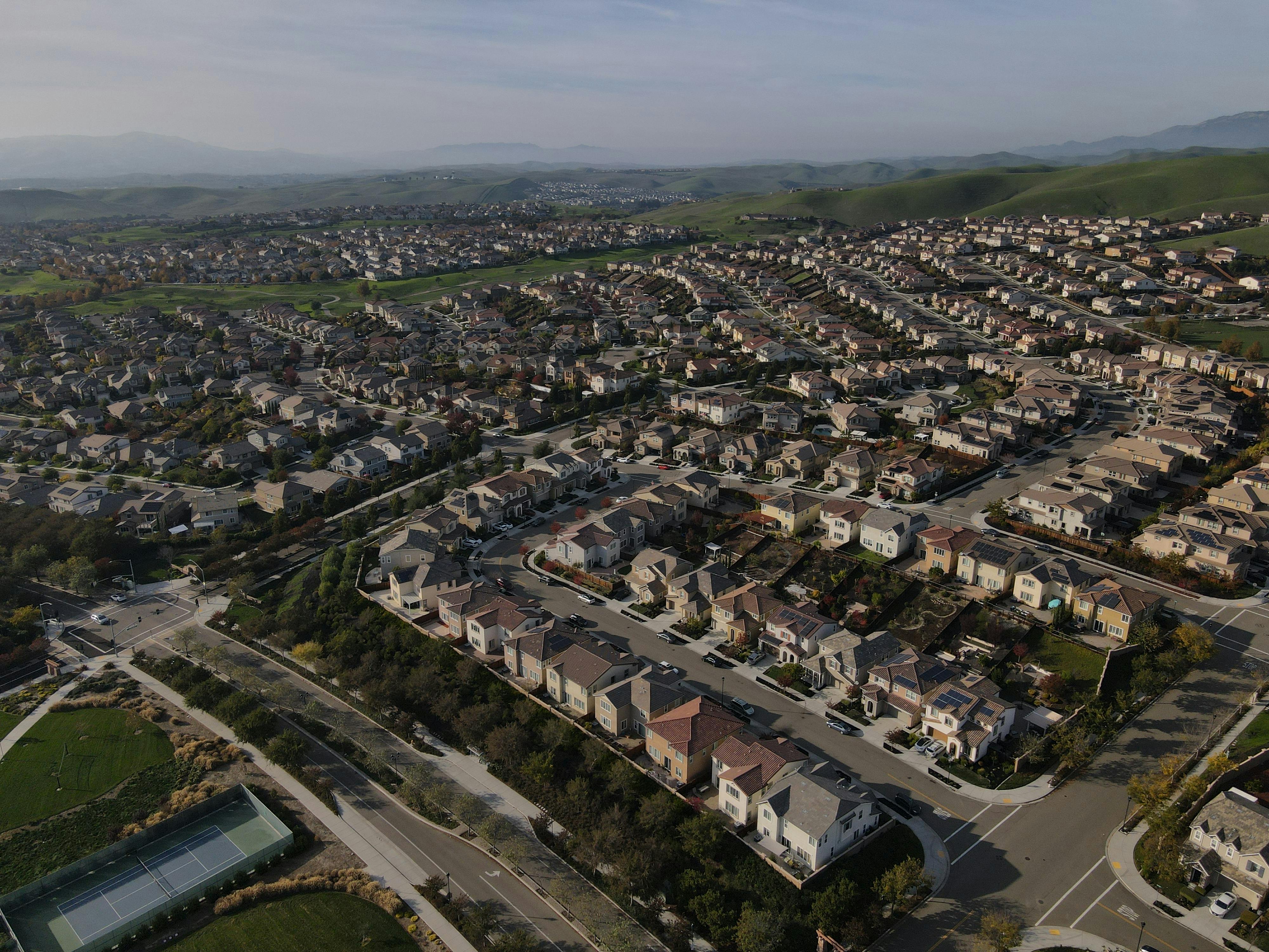 Aerial view of a residential neighborhood with rolling hills — community infrastructure and shared prosperity